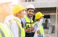 Group of contractors, engineers and formats in safety vests with helmets stand on the under-construction building site. teamwork Royalty Free Stock Photo