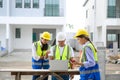 Group of contractors, engineers and formats in safety vests with helmets working with laptop, standing on under-construction Royalty Free Stock Photo