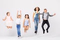 Group of cool boys and girls jumping up in white room