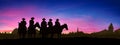 Group of cowboys on horseback at sunset