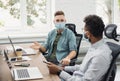 Group of coworkers people discussing business ideas while working in the office wearing medical protective face masks