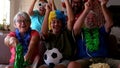 Group of crazy and coloured football supporter celebrate and exult during the match - mixed ages of caucasian people family and