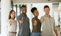 Group of creative colleagues smiling and gesturing thumbs up in creative office. Diverse business team standing together Royalty Free Stock Photo