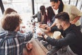 Group of creative multietnic friends sitting at wooden table. People having fun while playing board game