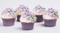 A group of cupcakes decorated with purple flowers.