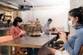 Group of customer dining in restaurant. Waitress with face mask preparing food for customer sit on social distancing table for new