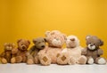 Group of cute brown teddy bears sit on yellow background, childrens toy Royalty Free Stock Photo