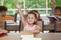 group Cute little girl student raising hands in classroom school . genius kid hand up . Great idea . child clever sitting at desk Royalty Free Stock Photo