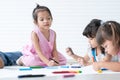 Group of cute little kids girls drawing on paper while sitting and lying on the floor. Adorable happy diversity children drawing Royalty Free Stock Photo