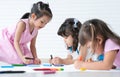 Group of cute little kids girls have fun drawing on paper while sitting and lying on the floor. Adorable happy diversity children Royalty Free Stock Photo