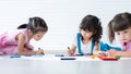 Group of cute little kids girls have fun drawing on paper while sitting and lying on the floor. Adorable happy diversity children Royalty Free Stock Photo