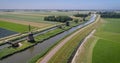 Group of Cyclists Passing Three Windmills, Typical Dutch Landscape - Rustenburg, The Netherlands, 4K Drone Footage