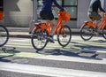 Group of cyclists on rented public bikes cross the road at crossroads