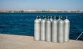 Cylinders with helium on dock. ten white cylinders for divers on sea dock. oxygen tanks for divers on pier. Royalty Free Stock Photo