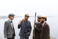 A group of gangsters in suits and with weapons are discussing something. Retro. Outdoors.