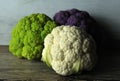 Group of different colored cauliflowers on wooden table