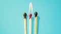 Group of different matches, some burning, pastel blue background, leadership, idea generation, teamwork. Generative AI Royalty Free Stock Photo