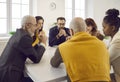 Group of different men and women sitting around table and praying to God together Royalty Free Stock Photo