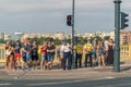A group of different people is waiting for a pedestrian traffic light.