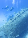 Group of divers above the wreck of old ship at the bottom of tropical sea, underwater landcape.