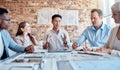 Group of diverse architects discussing plans, blueprints and schematics during a meeting in their office boardroom Royalty Free Stock Photo