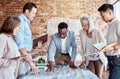 Group of diverse architects discussing plans, blueprints and schematics during a meeting in their office boardroom Royalty Free Stock Photo