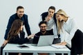 Group of diverse businesspeople going over paperwork together and working on a laptop at a table in an office Royalty Free Stock Photo