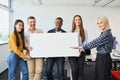 Group of diverse casual business people standing in office holding banner Royalty Free Stock Photo