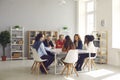 Group of diverse company employees sitting at big table in corporate office meeting