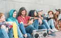 Group of diverse friends having fun outdoor - Millennial young people using mobile phones and listening music with vintage boombox Royalty Free Stock Photo