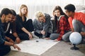 Group of diverse friends looking at map in the bright room