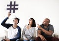 Group of diverse friends sitting on couch holding a hashtag icon Royalty Free Stock Photo