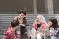 A group of diverse, multiracial young Asian university students are seen resting and chatting outdoors sitting on steps Royalty Free Stock Photo