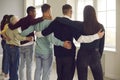 Group of diverse people stand in an embrace with their backs to the camera and look out the window. Royalty Free Stock Photo