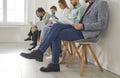 Group of men and women sitting by office wall and waiting for business meeting or job interview Royalty Free Stock Photo