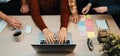 Group of diverse professionals collaborating on a project around a laptop at an office table with stationery and Royalty Free Stock Photo