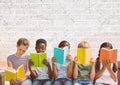 Group of diverse students reading books against grey brick wall background with copy space Royalty Free Stock Photo
