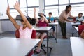 Group of diverse students using electronic devices while sitting on their desk in class at school Royalty Free Stock Photo