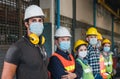 Group of diverse team of workers wearing face mask standing in front of the factory