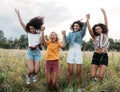 Group of diverse women jumping together outdoors. Friends having fun during vacation