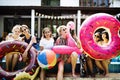 Group of diverse women sitting by the pool with inflatable tubes Royalty Free Stock Photo
