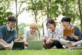 A group of diverse young Asian college students sitting on the grass enjoy talking in the park Royalty Free Stock Photo