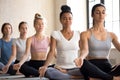 Group of attractive women practicing yoga in Ardha Padmasana pose