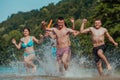 A group of diverse young people having fun together as they run along the river and play water games Royalty Free Stock Photo