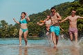 A group of diverse young people having fun together as they run along the river and play water games Royalty Free Stock Photo