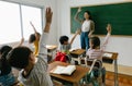 Group of diversity of elementary school kids raise arm up to answer teacher question in classroom. Education, elementary school, Royalty Free Stock Photo