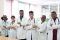 A group of doctors in the hospital corridor. Team of mixed race young men in white coats, with phonendoscopes, smiling Royalty Free Stock Photo