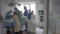 Group of doctors perform an operation in the operating room. Team of medical worker wearing masks and uniforms. City
