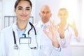 Group of doctors showing OK or approval sign with thumb up. High level and quality medical service, best treatment and Royalty Free Stock Photo