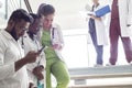 A group of doctors on the steps in the hospital. Young people of mixed race, in medical clothes, examine X-rays, use a smartphone Royalty Free Stock Photo